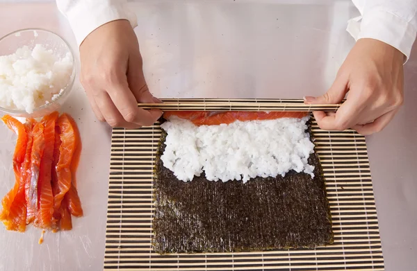 Koch macht Sushi-Brötchen mit Lachs — Stockfoto