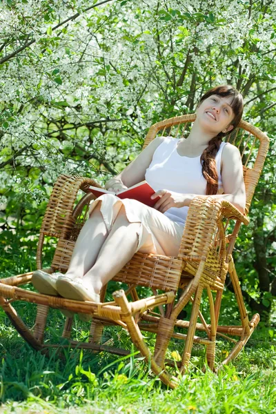 Çiçek bahçesinde rahatlatıcı kız okuma kitabı — Stok fotoğraf