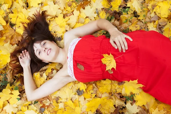 Jonge vrouw ligt in herfst park — Stockfoto
