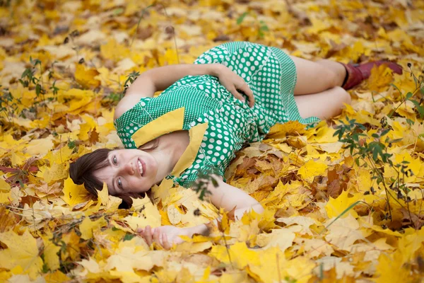 Girl lies in maple leaves — Stock Photo, Image