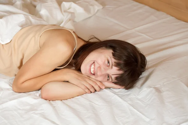 Ευτυχισμένη γυναίκα ξαπλωμένη στο κρεβάτι — Φωτογραφία Αρχείου