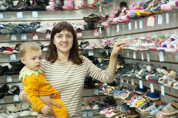 Mãe feliz com criança escolhe sapatos de bebê — Fotografia de Stock