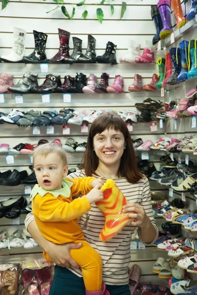 Женщина с ребенком выбирает сапоги — стоковое фото