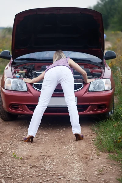 Sexy chica buscando debajo de la capucha del coche — Foto de Stock