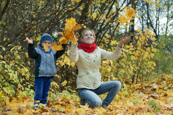 Mãe com menino jogando folhas de bordo — Fotografia de Stock
