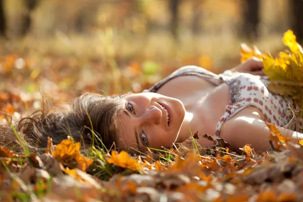 Jonge vrouw ligt in eikenbladeren — Stockfoto