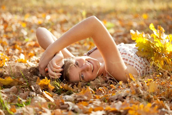 Happy girl lies in autumn park — Stock Photo, Image