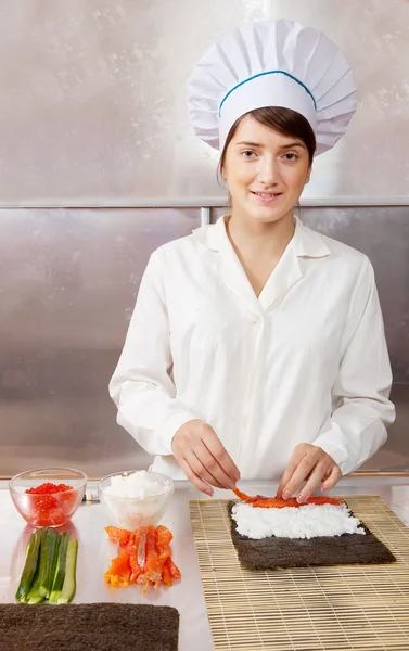 Cook woman making sushi rolls