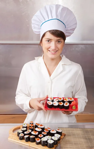 Cook woman with cooked sushi rolls — Stock Photo, Image