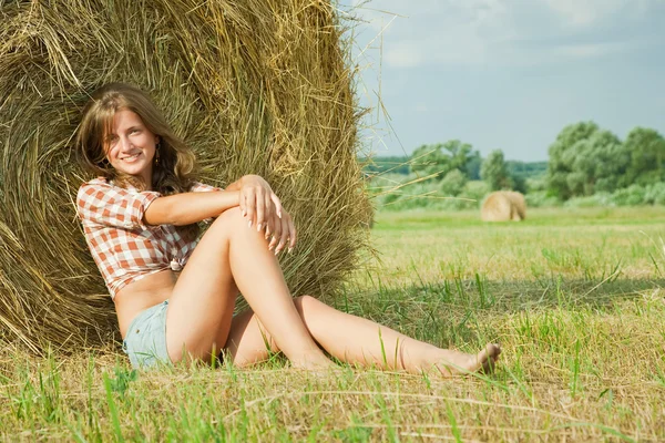 Girl resting on straw bale — Stockfoto