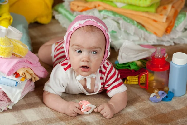 Bambina con mucchio di abbigliamento del bambino — Foto Stock
