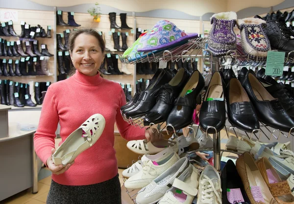 Vrouw kiest schoenen bij shop — Stockfoto