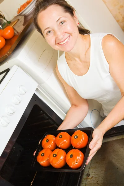Женщина жарит фаршированные помидоры — стоковое фото