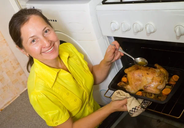 Woman roasting chicken — Stock Photo, Image