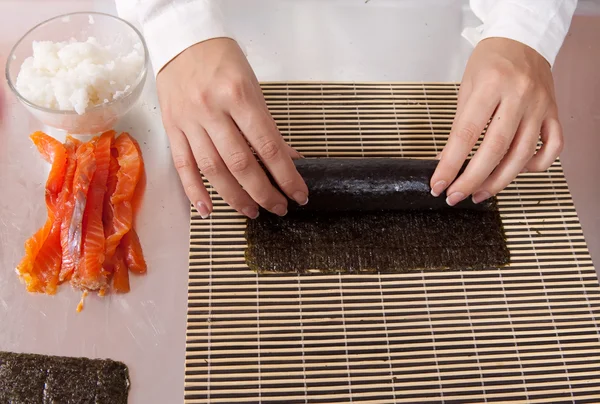 Cozinhe fazendo rolos de sushi com salmão — Fotografia de Stock