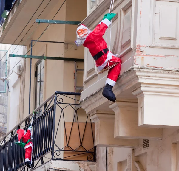 Санта Клаус карабкается вверх по дому — стоковое фото