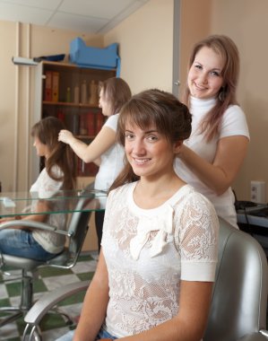 Stylist works on woman hair in salon clipart