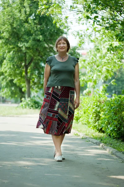 Mogen kvinna promenader i parken — Stockfoto