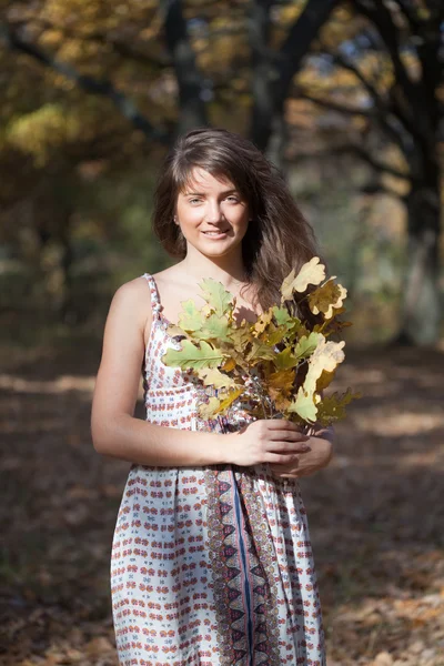 Lány oak levelek jelige őszi parkban — Stock Fotó
