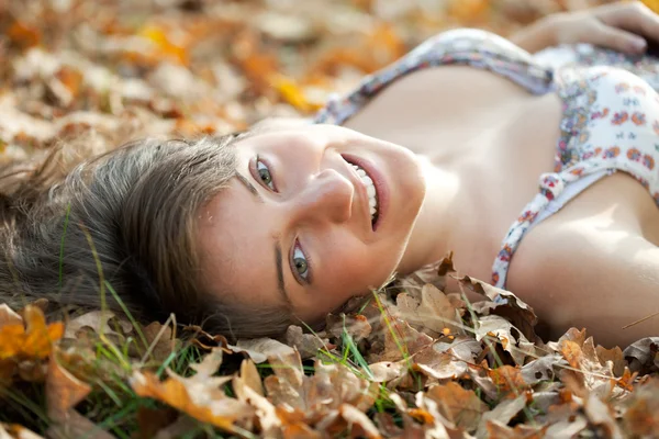 Menina feliz jaz em folhas de carvalho — Fotografia de Stock
