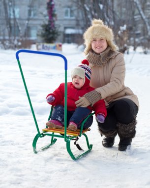 Mother with toddler on sled in winter clipart