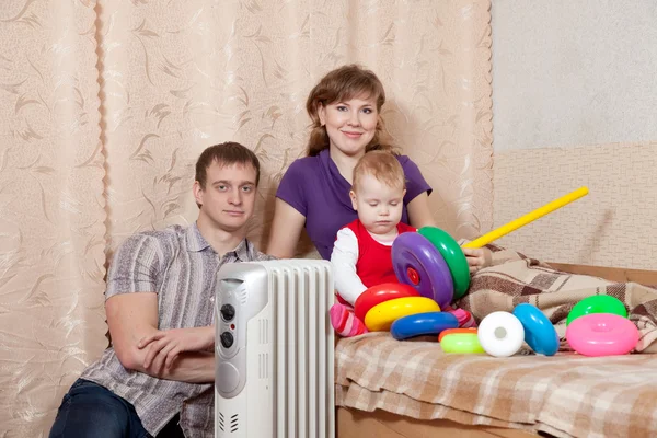 Família em casa perto de aquecedor de óleo — Fotografia de Stock