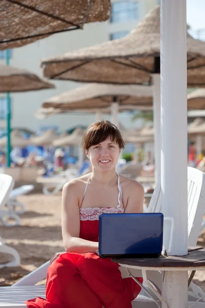 便携式计算机在海滩度假村的女人 — 图库照片