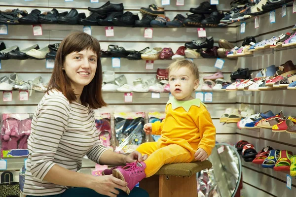 stock image Woman with child chooses baby shoes