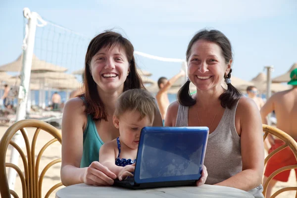 Women and girl with laptop at beach — Stock Photo, Image
