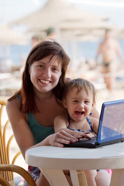 Madre feliz y niño pequeño con portátil en la playa — Foto de Stock