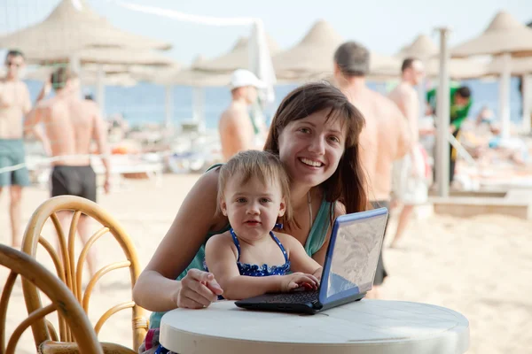 Gelukkig moeder en peuter met laptop op strand — Stockfoto