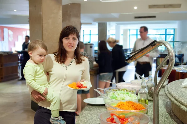Frau mit Kind wählt Gemüse am Buffet — Stockfoto