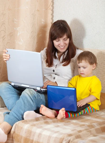 Glad kvinna med barn som använder bärbara datorer — Stockfoto
