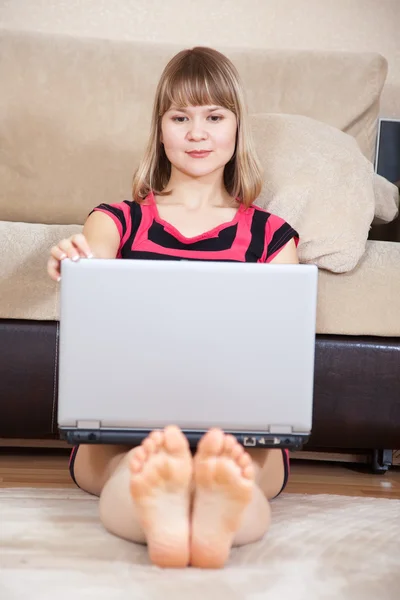 Девушка сидит на полу и использует ноутбук — стоковое фото