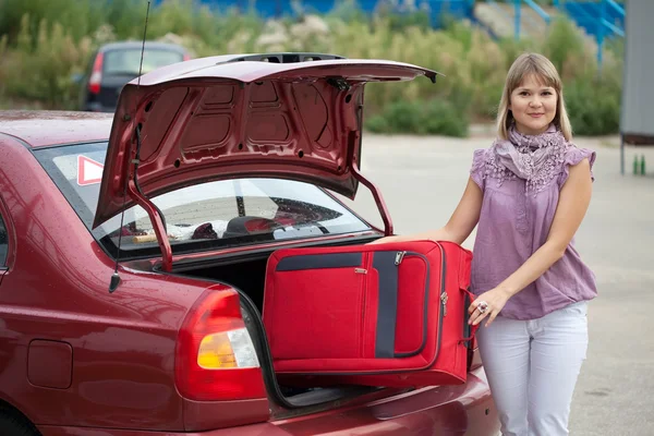 Dívka dá kufr v autě — Stock fotografie