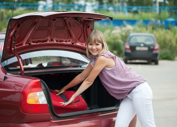 Woman packing her baggage into car — Stock Photo, Image