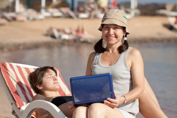 Zralá žena s laptopem na pláži — Stock fotografie