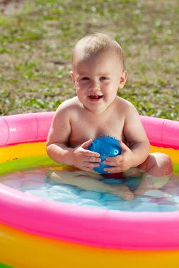 Happy baby swimming in inflatable pool clipart