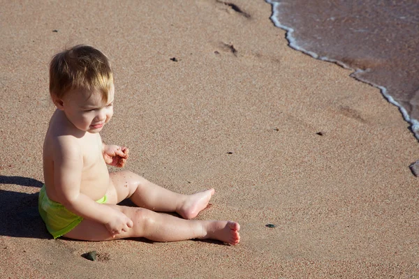 Kum plajı üzerinde yürümeye başlayan çocuk oturur — Stok fotoğraf