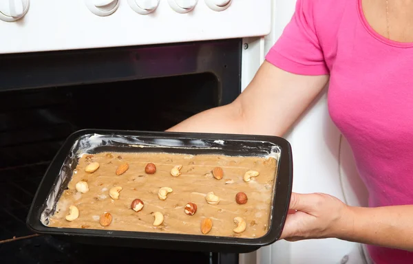 Female hands putting dough into oven — Stock Photo, Image