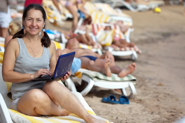 Ha ppy mature woman with laptop at resort — Stock Photo, Image