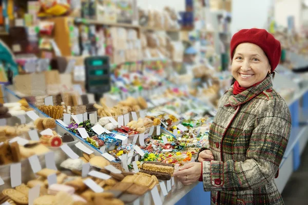 Mature woman chooses sweets — Stock Photo, Image