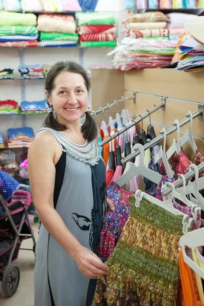 Mogen kvinna väljer klä vid butik — Stockfoto
