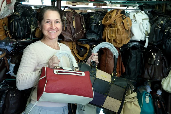 Mature woman chooses leather bag — Stock Photo, Image