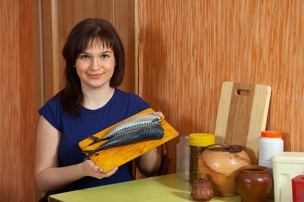 Vrouw houdt cuting bord met scombrus — Stockfoto