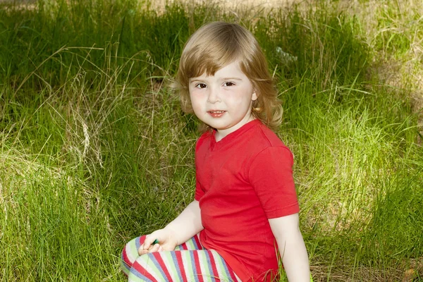 Malá holčička seděli na trávě — Stock fotografie