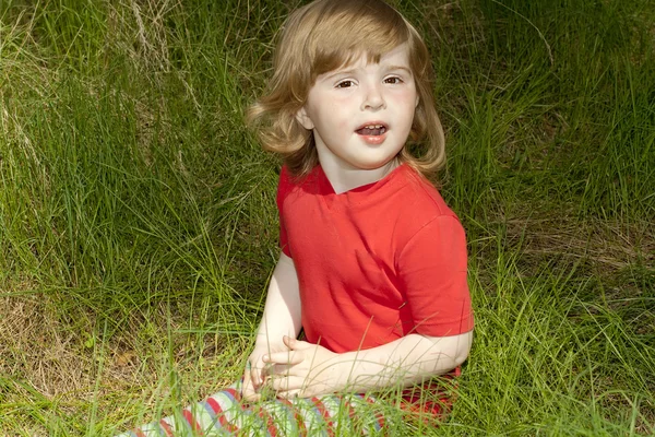 Une petite fille assise dans l'herbe — Photo