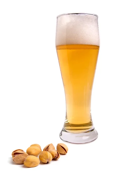 Light beer with the foam in a tall glass and pistachios — Stock Photo, Image