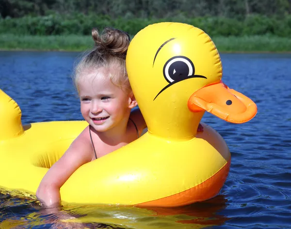 Klein meisje baadt in rivier in opblaasbare eend — Stockfoto