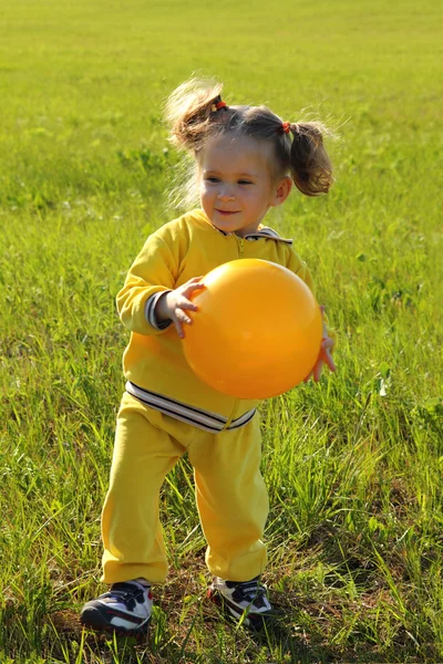 Liten flicka med bollen på äng — Stockfoto